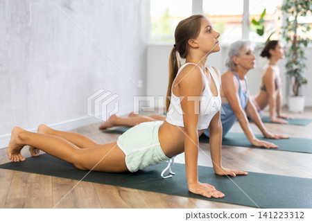 Teenage girl doing yoga in group in studio Teenage girl doing yoga in group in studio 141223312