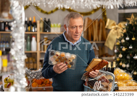 Happy elderly couple choosing nougat and panellets for Christmas table in grocery shop Happy elderly couple choosing nougat and panellets for Christmas table in grocery shop 141223399
