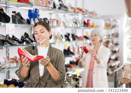 In large shoe store,young woman is looking at high heel shoes 141223400