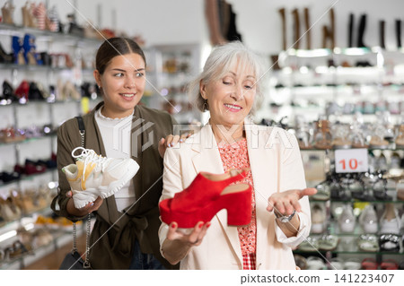Mom with an adult daughter choose and buy fashionable high heeled shoes in a shoe store Mom with an adult daughter choose and buy fashionable high heeled shoes in a shoe store 141223407