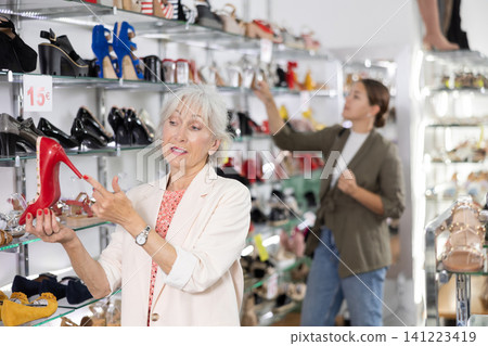 Elderly woman chooses stilettos in shoe store Elderly woman chooses stilettos in shoe store 141223419