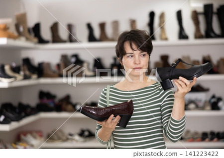 Adult woman chooses classic shoes in shoe store 141223422