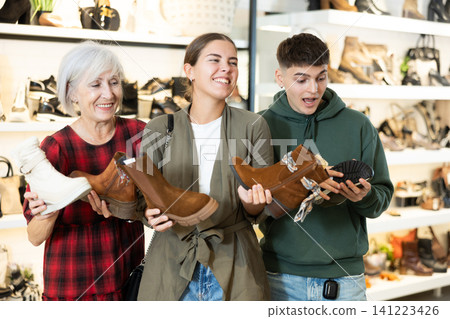 Happy family discussing models of ankle boots in shoe store Happy family discussing models of ankle boots in shoe store 141223426