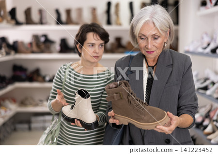 Adult and elderly women choosing boots in store 141223452