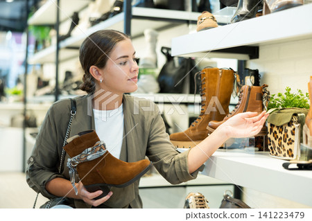 Young woman choosing ankle boots in store Young woman choosing ankle boots in store 141223479
