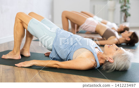 Mom, grandma and teen daughter do half bridge Setu Bandha Sarvangasana, glute bridge pose Mom, grandma and teen daughter do half bridge Setu Bandha Sarvangasana, glute bridge pose 141223497