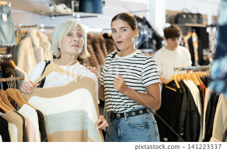 Two women choosing convenient jumper in clothing store Two women choosing convenient jumper in clothing store 141223537