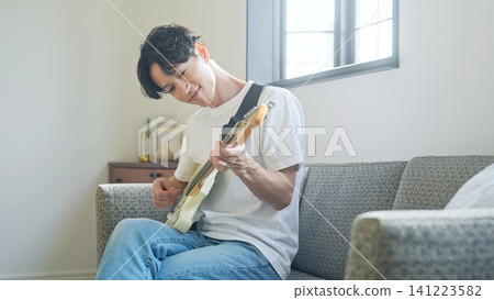 一名男子正在彈奏電吉他。音樂、樂器、表演、練習、興趣、樂團、音樂家、吉他手 141223582