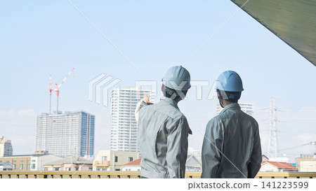 A group of male workers looking out at a city under construction. (Keywords: construction, teamwork, safety, inspection, building, site, building maintenance, inspection) A group of male workers looking out at a city under construction. (Keywords: construction, teamwork, safety, inspection, building, site, building maintenance, inspection) 141223599