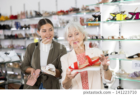 Elderly woman and young woman choosing sandals in shoe store Elderly woman and young woman choosing sandals in shoe store 141223710