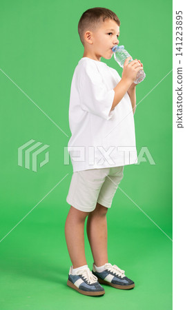 Boy with bottle of water quenches thirst 141223895