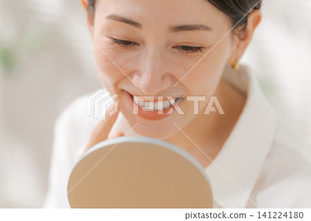 A woman looking at her mouth in the mirror A woman looking at her mouth in the mirror 141224180