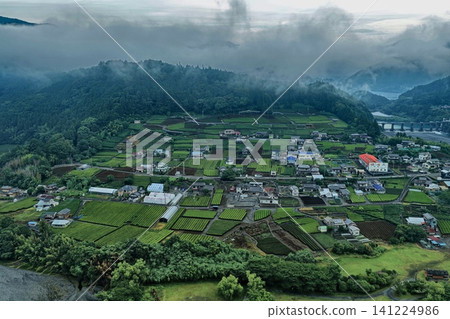 一張空拍照片,展現了靜岡縣久乃脅村的居民點和農田,以及籠罩在薄霧中的山脈。 一張空拍照片,展現了靜岡縣久乃脅村的居民點和農田,以及籠罩在薄霧中的山脈。 141224986