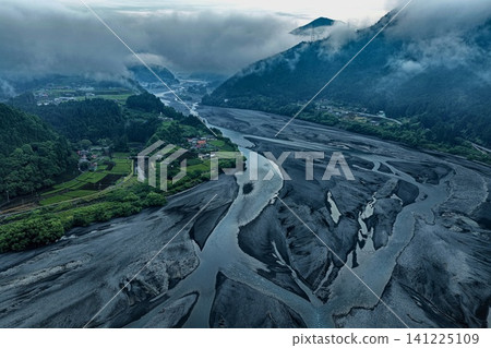 An aerial photograph overlooking the Kunowaki settlement and riverbed in the upper reaches of the Oi River in Shizuoka Prefecture, amidst the summer morning mist. An aerial photograph overlooking the Kunowaki settlement and riverbed in the upper reaches of the Oi River in Shizuoka Prefecture, amidst the summer morning mist. 141225109