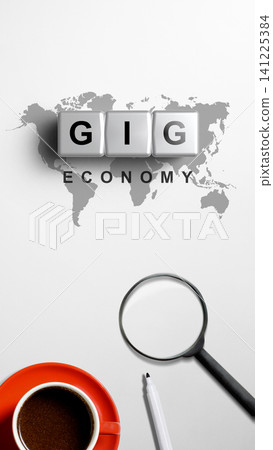 A vertical overhead shot showcasing the words 'Gig Economy' with a world map, coffee cup, and magnifying glass on a white desk A vertical overhead shot showcasing the words 'Gig Economy' with a world map, coffee cup, and magnifying glass on a white desk 141225384