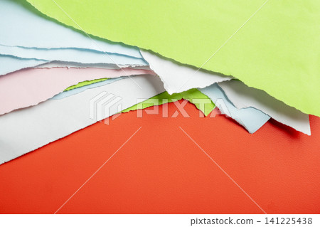 Vibrant abstract composition made of layered torn sheets of colored paper including red, green, blue, pink, and white, showing rough ripped edges 141225438