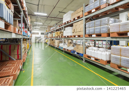 Clean industrial warehouse interior with organized goods stored on metal shelves and a green floor with yellow safety lines Clean industrial warehouse interior with organized goods stored on metal shelves and a green floor with yellow safety lines 141225465