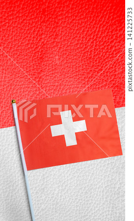 A small flag of Switzerland placed diagonally on a split red and white textured leather surface. Concept of Swiss National Day A small flag of Switzerland placed diagonally on a split red and white textured leather surface. Concept of Swiss National Day 141225733