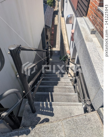 Steep stairs with handrails installed in the gaps between houses and buildings Steep stairs with handrails installed in the gaps between houses and buildings 141225843
