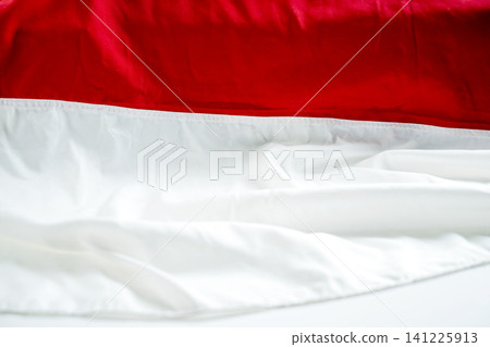 Close-up of red and white draped fabrics representing the Indonesian flag. Textured abstract background with soft folds for patriotic themes, national day, and celebrations 141225913