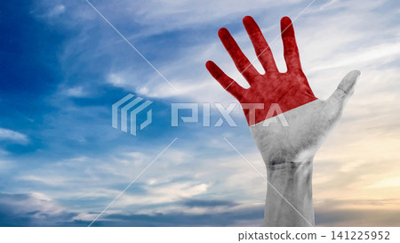 A close-up shot of a human hand raised against a blue sky, painted with the colors of the Indonesian national flag, representing patriotism, unity, and national pride A close-up shot of a human hand raised against a blue sky, painted with the colors of the Indonesian national flag, representing patriotism, unity, and national pride 141225952