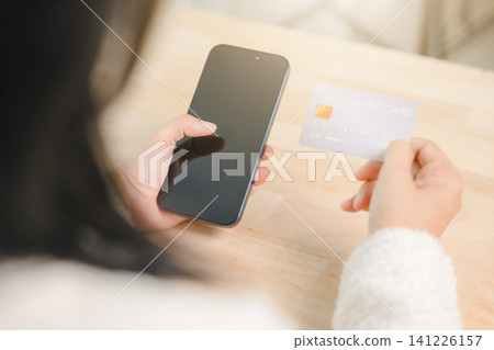 Paying and shopping with credit card and mobile phone in computer home business concept, woman holding smartphone and credit card for online payment and ecommerce transfer Paying and shopping with credit card and mobile phone in computer home business concept, woman holding smartphone and credit card for online payment and ecommerce transfer 141226157