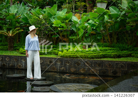 Woman walks on stones in a garden with green plants Woman walks on stones in a garden with green plants 141226307