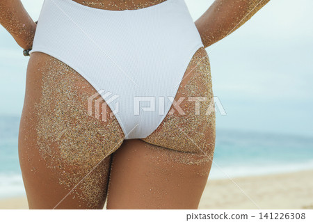 Person standing on sandy beach near the ocean Person standing on sandy beach near the ocean 141226308