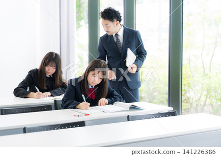 圖片顯示了日本國中和高中女生在補習班或學校的教室裡接受老師一對一輔導的場景。 141226386