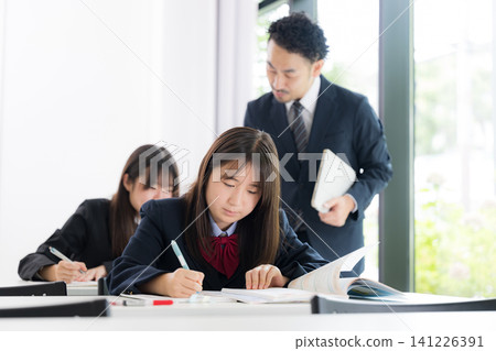 Japanese junior high and high school girls studying with teachers who provide individual tutoring in cram schools and school classrooms. Japanese junior high and high school girls studying with teachers who provide individual tutoring in cram schools and school classrooms. 141226391