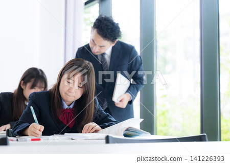 日本國中和高中女生在補習班和學校教室接受老師的一對一輔導。 141226393