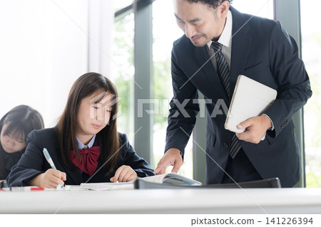 日本國中和高中女生在補習班和學校教室接受老師的一對一輔導。 141226394