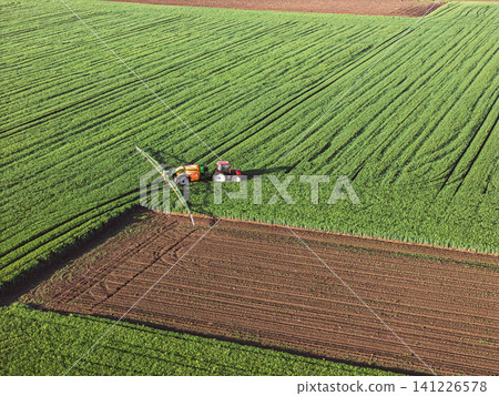 A farmer sprays fertilizer on several fields planted with different crops. Top view A farmer sprays fertilizer on several fields planted with different crops. Top view 141226578