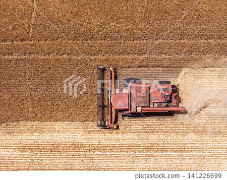 Grain harvest machinery operating in field, top down drone view 141226699