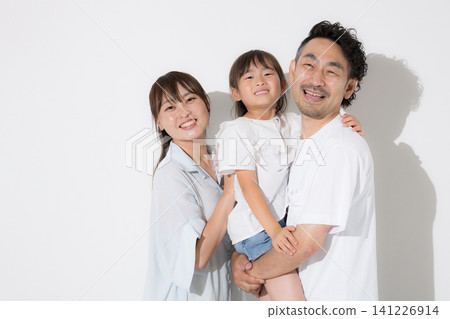 一家人在白色背景前笑容燦爛——幸福的家庭生活和健康的生活方式，穿著短袖，拍攝夏季度假照，直視鏡頭。 141226914