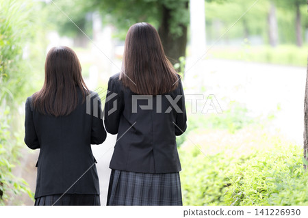 兩位友善的日本高中女生在綠色的戶外背景下微笑;她們一起度過了高中生活和青春;她們的臉被遮住了,只露出了背影。 兩位友善的日本高中女生在綠色的戶外背景下微笑;她們一起度過了高中生活和青春;她們的臉被遮住了,只露出了背影。 141226930