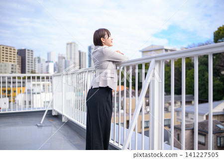 一位女商人站在樓頂，凝視著遠方。 141227505