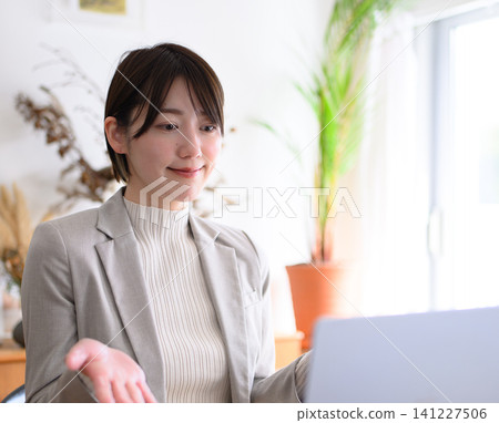 一位女士一邊看著筆記型電腦一邊說話。 141227506