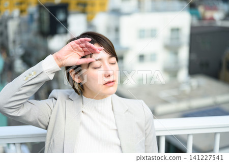 A woman puts her hand to her forehead because of the heat. A woman puts her hand to her forehead because of the heat. 141227541