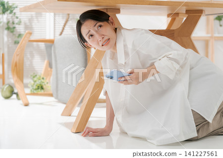 Woman hides under the desk Woman hides under the desk 141227561