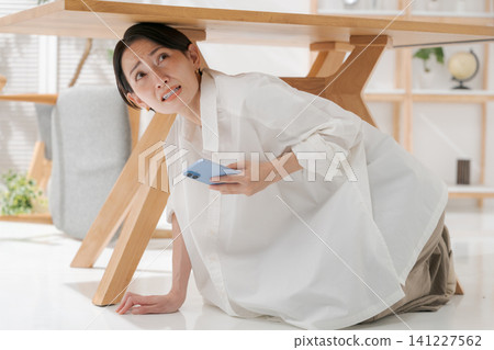 Woman hides under the desk Woman hides under the desk 141227562