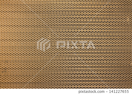 A golden metal filter plate with a fine, overlapping grid-like mesh pattern. A golden metal filter plate with a fine, overlapping grid-like mesh pattern. 141227655