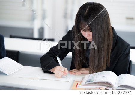 日本高中女生在教室裡認真學習;學生們獨立學習,準備入學考試和常規考試。 日本高中女生在教室裡認真學習;學生們獨立學習,準備入學考試和常規考試。 141227774