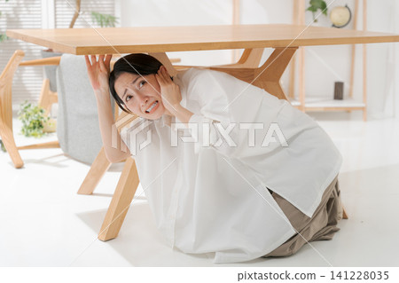 Woman takes shelter under a desk during earthquake Woman takes shelter under a desk during earthquake 141228035