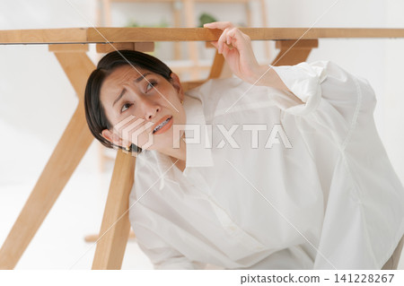 一個女人爬到桌子底下。 一個女人爬到桌子底下。 141228267