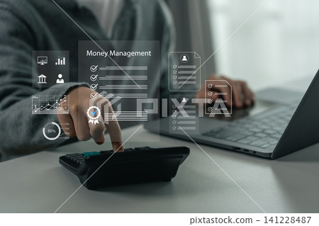 Person using calculator for financial calculation with transparent digital interface icons displaying money management concepts and data analytics on desk with laptop computer Person using calculator for financial calculation with transparent digital interface icons displaying money management concepts and data analytics on desk with laptop computer 141228487