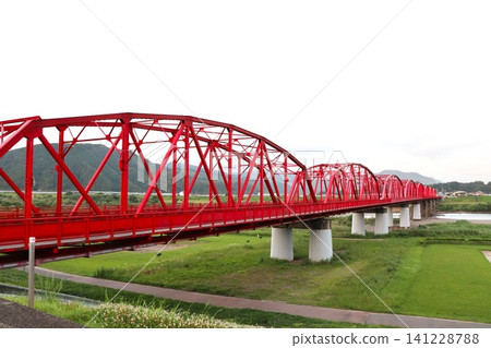 A red iron bridge spanning a lush natural landscape A red iron bridge spanning a lush natural landscape 141228788