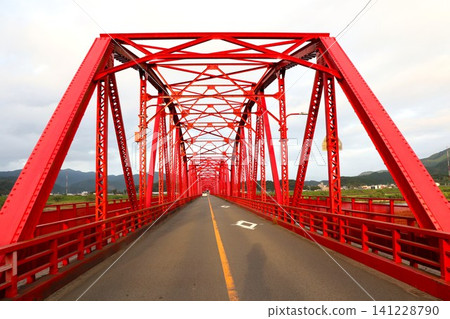 A frontal view of a railway bridge with a series of red trusses. A frontal view of a railway bridge with a series of red trusses. 141228790