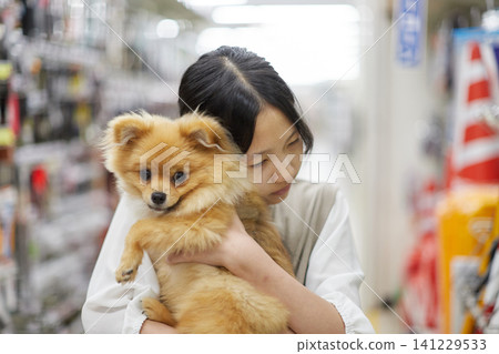 A teenage girl shopping at a home improvement store with her cute Pomeranian puppy. A teenage girl shopping at a home improvement store with her cute Pomeranian puppy. 141229533