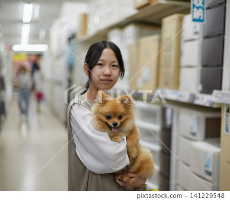 A teenage girl shopping at a home improvement store with her cute Pomeranian puppy. 141229548